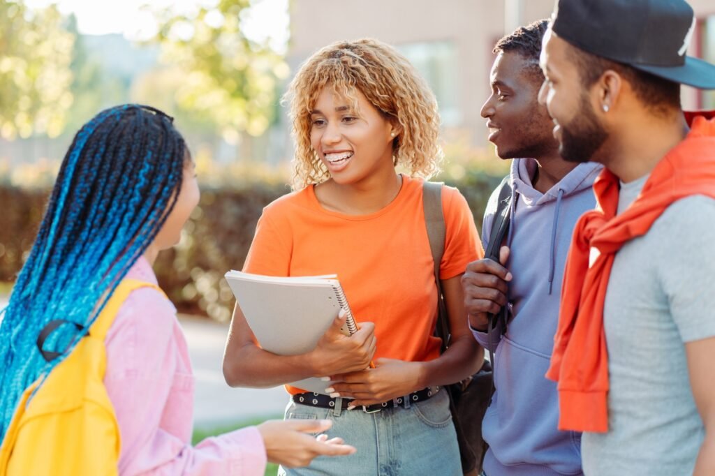 Group of smiling stylish African American student with books and backpacks, talking