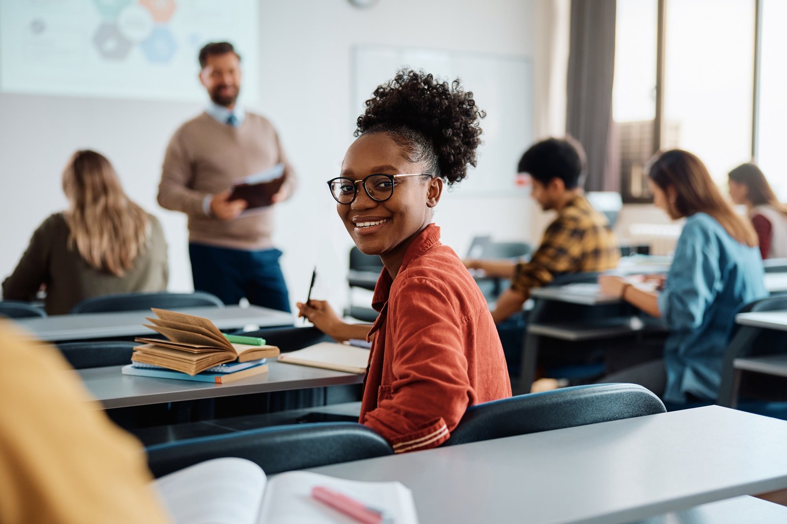 Happy black university student attending a lecture in the classroom and looking at camera.